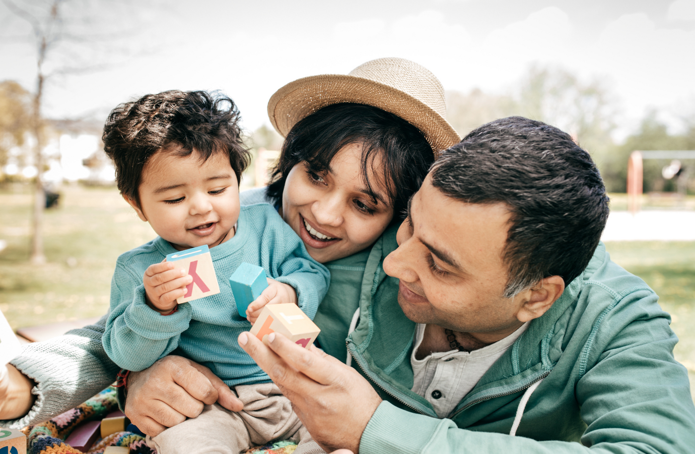 Parents watching their child while playing blocks.