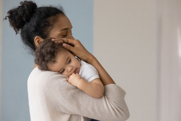 A mother gently cradling a baby in her arms.