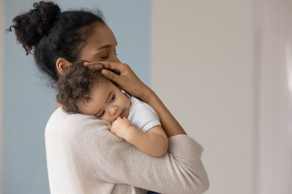 A mother gently cradling a baby in her arms.