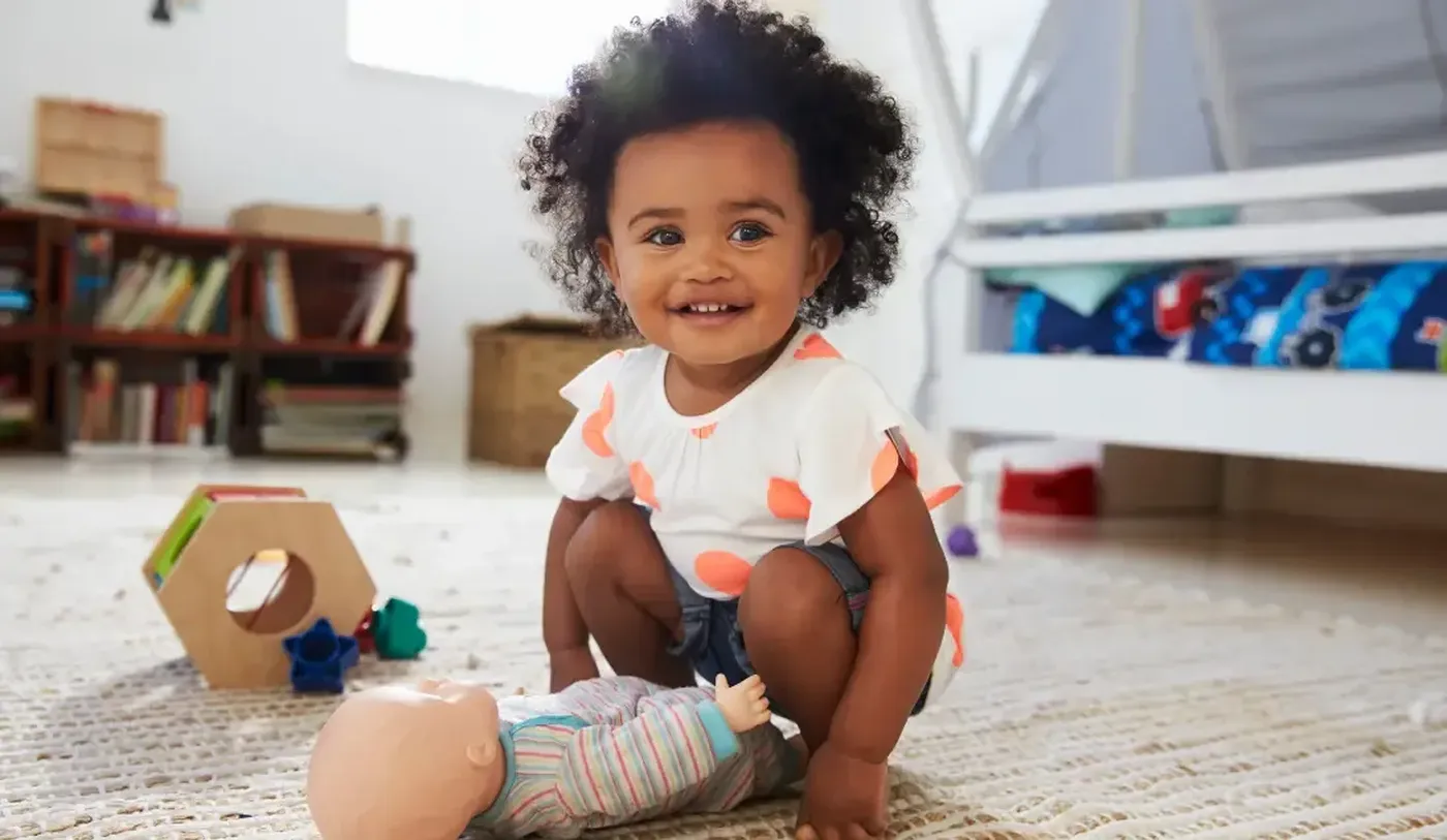 Toddler playing in her bedrom with a doll